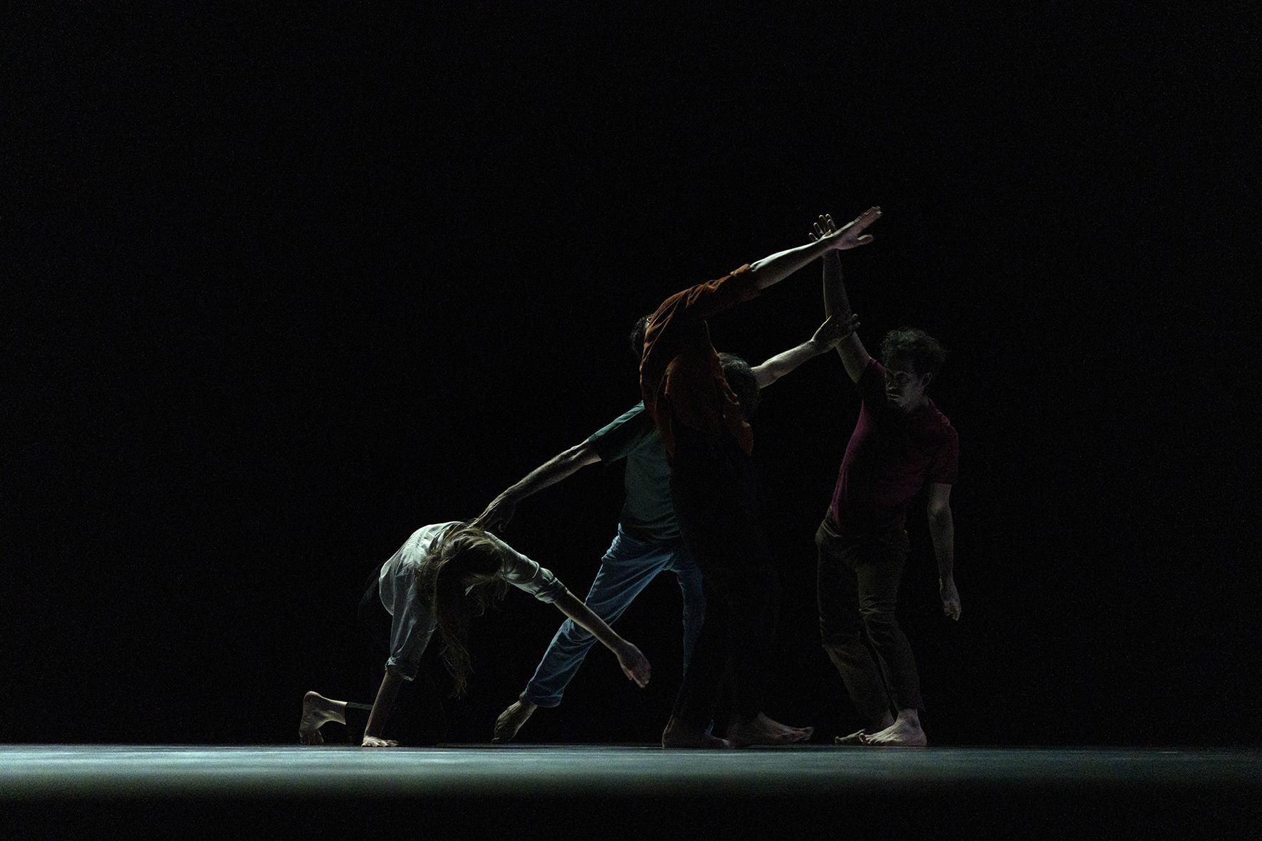 Dancers creating a form on a dark stage