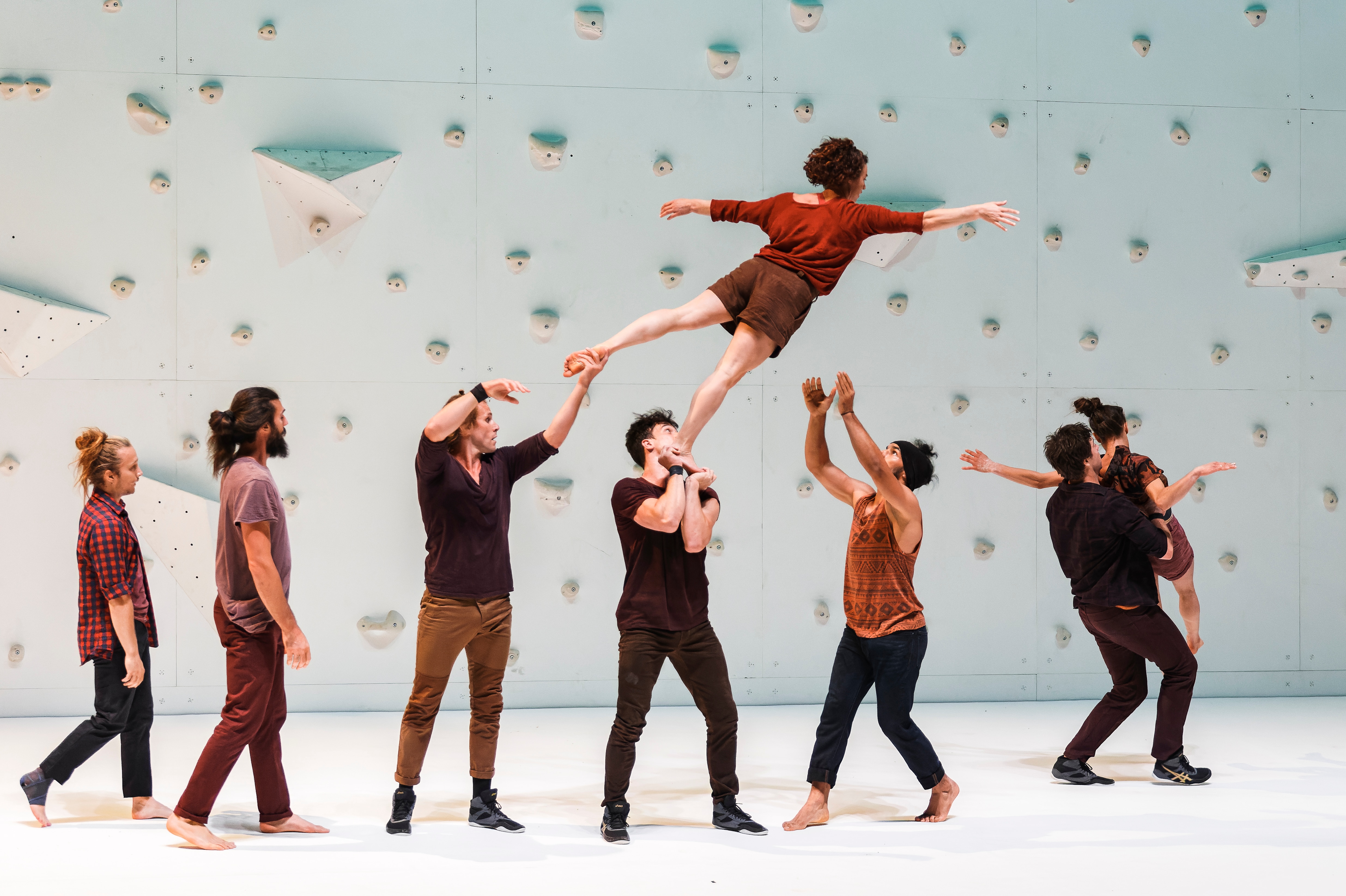 Danseurs devant un mur d’escalade balançant un danseur en l’air