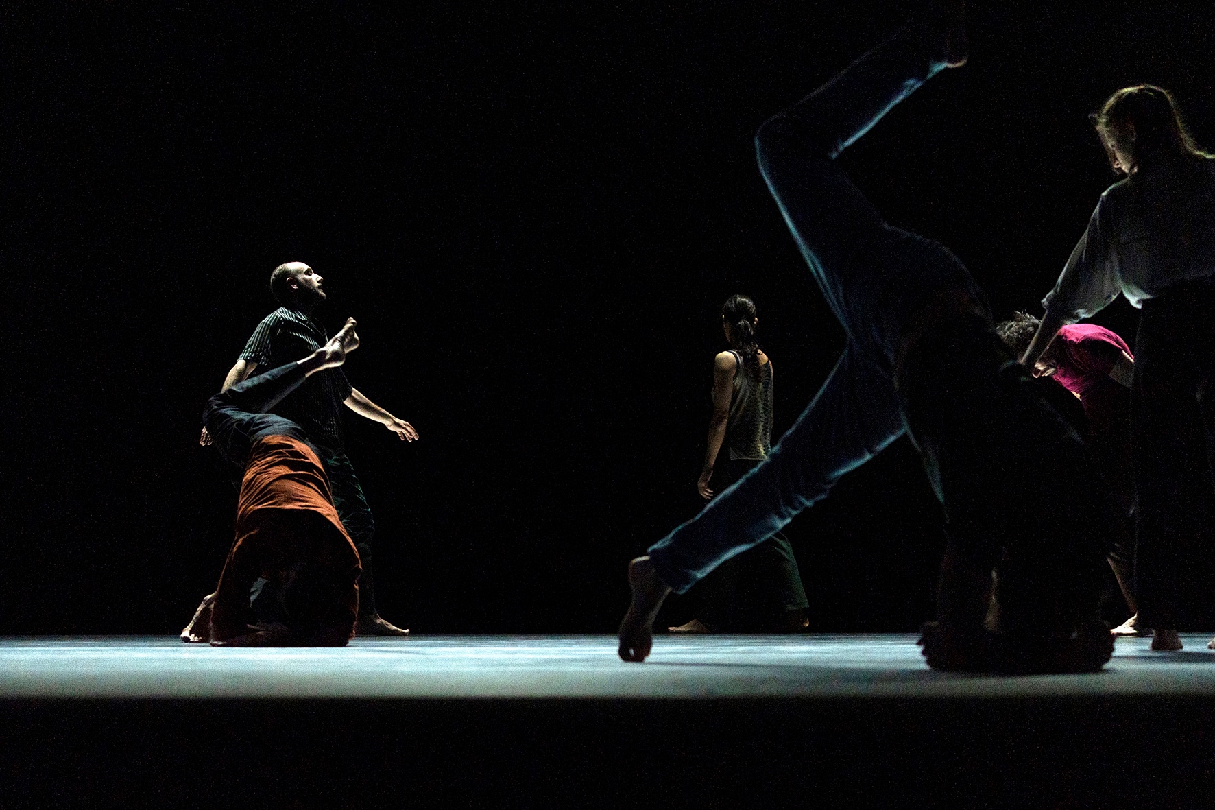 Dancers moving around on a dark stage