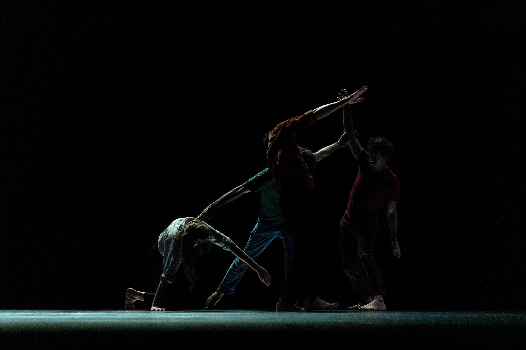 Dancers creating a form on a dark stage