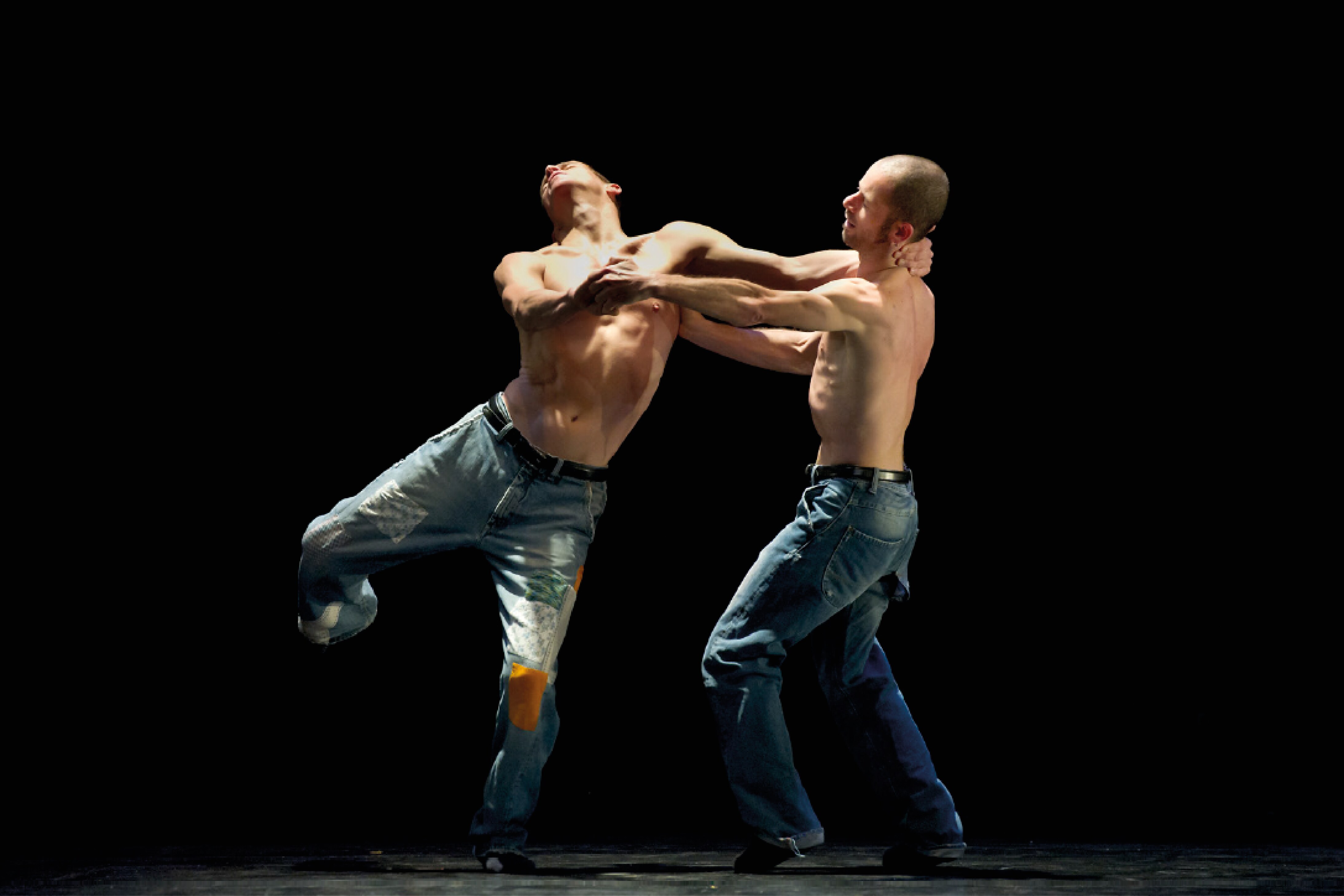 Deux danseurs en jeans et torses nus se tenant par les bras