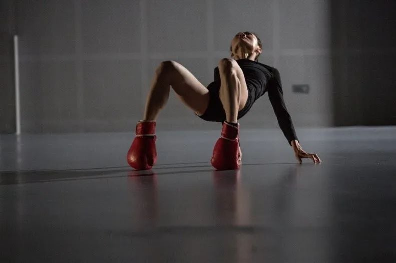 Dancer on the ground with boxing gloves on her feet