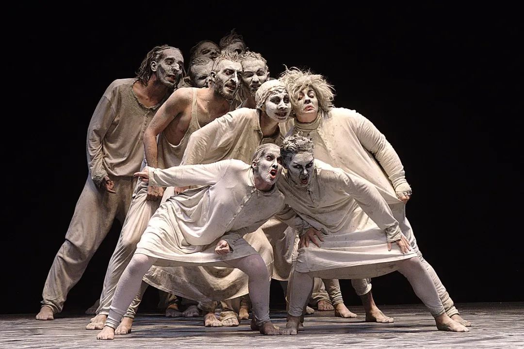 Dancers dressed in white on a dark stage