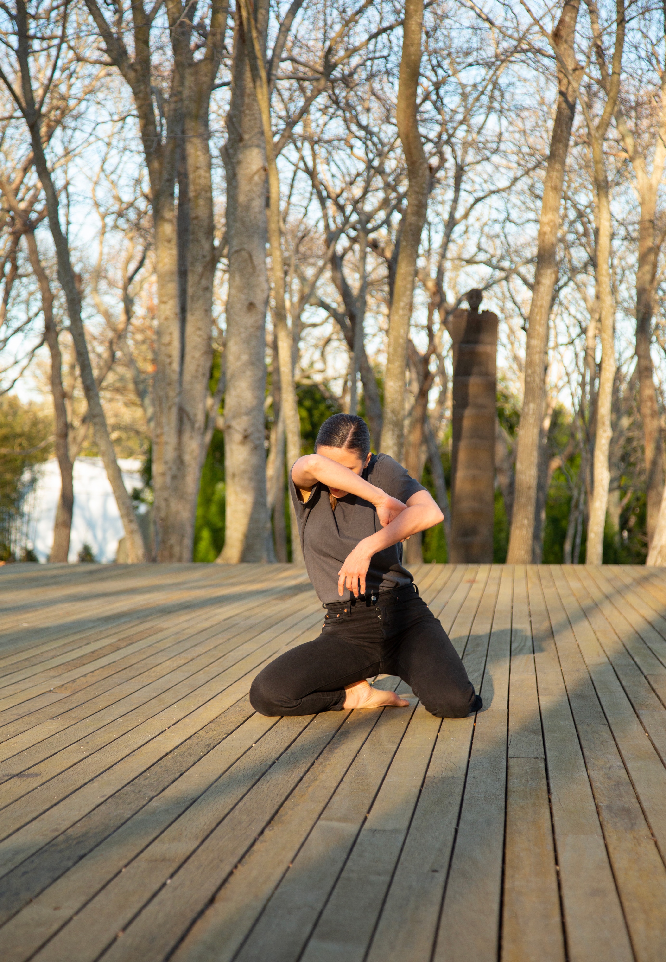 a dancer kneeling on an open-air terrace, her face buried in her arm.