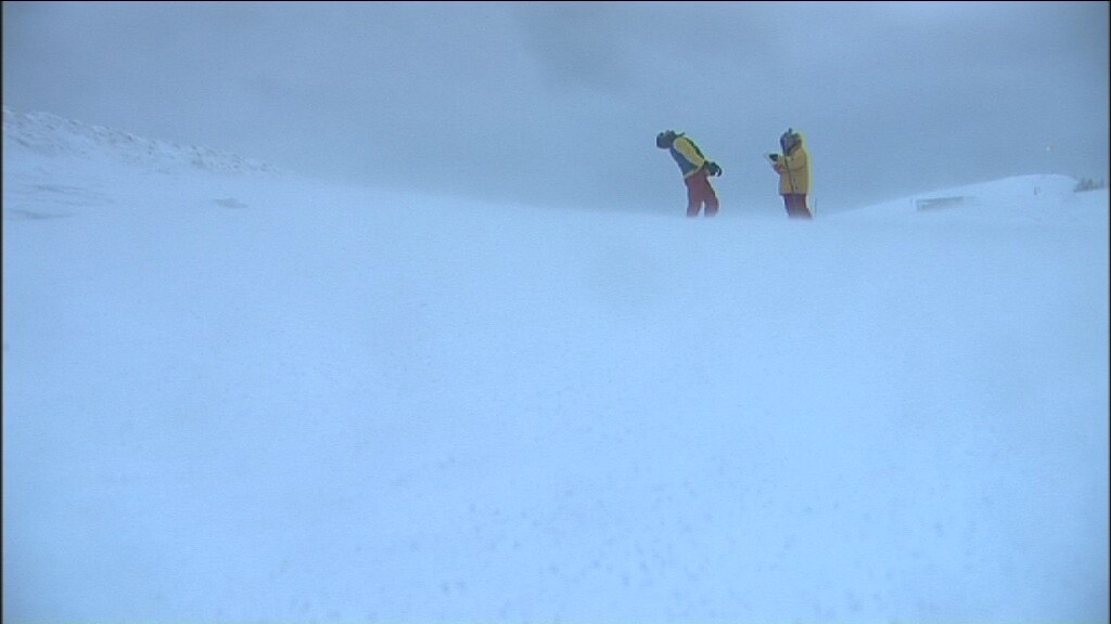 deux hommes en arrière-plan, sur un sol de neige et dans le brouillard 