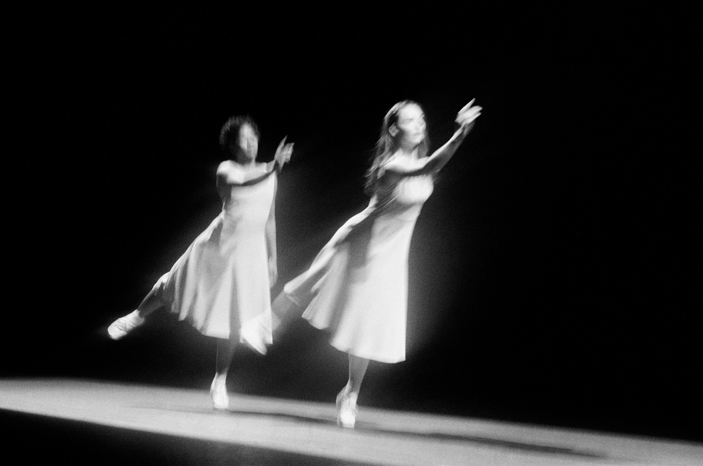 Two dancers jumping and raising their arms 