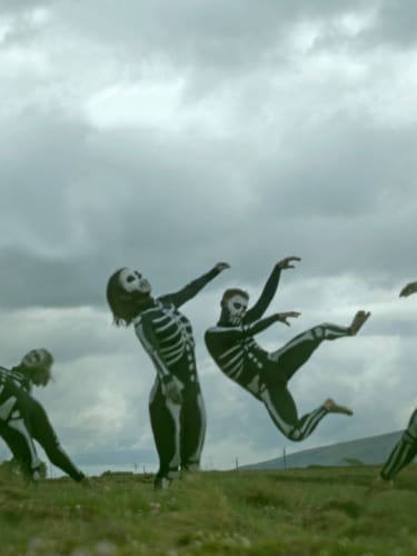Dancers disguised as skeletons in the grass.