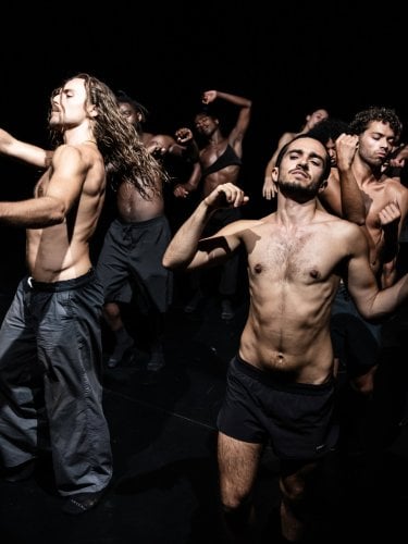 Five shirtless dancers in motion against a black background