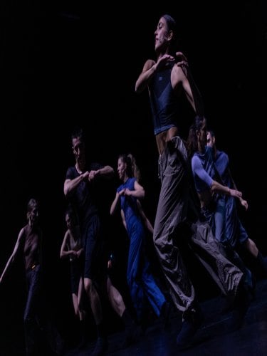seven people running to the left on a black background
