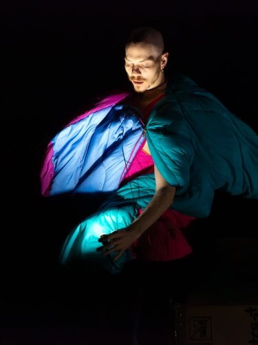 Homme entouré d'un duvet dans le noir. 
