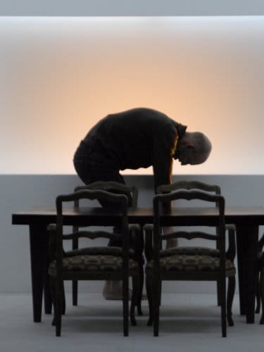 Homme entrain de se baisser derrière une table.