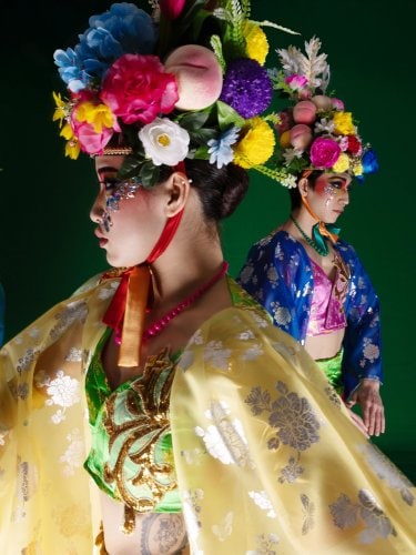 une femme en tenue traditonnelle jaune avec deux autres femmes derrière elle. 