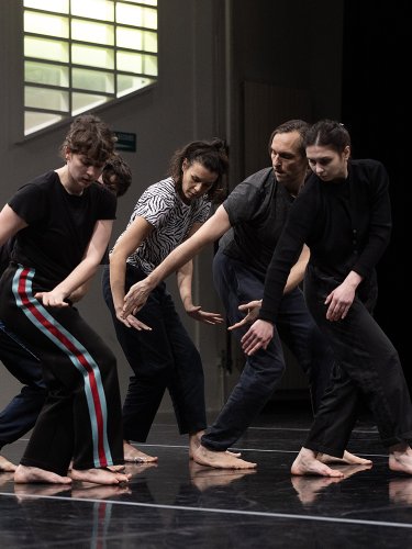 five dancers in a row in the same position, looking at their hands