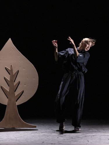 dancer next to a tree in a setting on a black background.