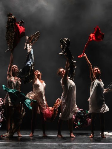Four women lined up throwing shirts and dresses upwards