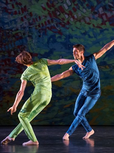 Two men, one in a green suit, the other in a blue suit on stage.