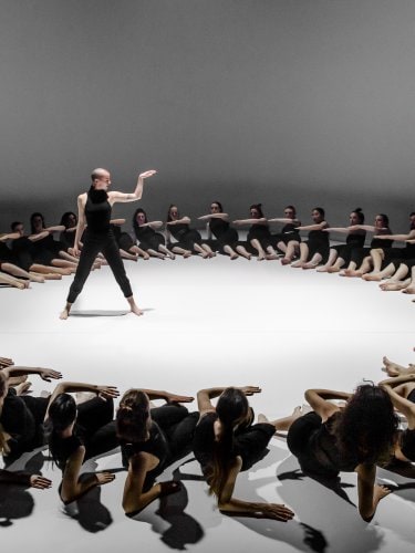 a dancer surrounded by a big cercle made by dancers lying on the stage