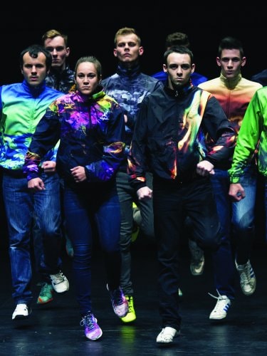 un groupe de danseurs en jean et vestes de sport marchant vers l'avant