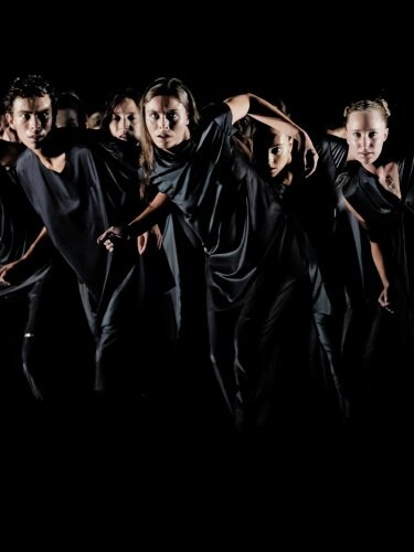 dancers in black moving as a group 