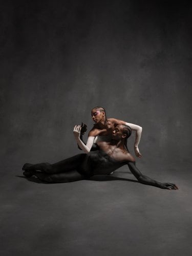 Two dancers with black and white body paint in a pose.