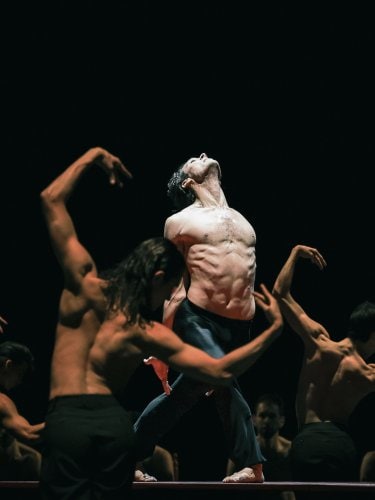topless dancer on a stage, in the center of a circle of dancers