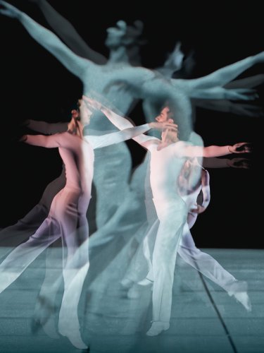 2 dancers in white jumping with their reflections on a black background
