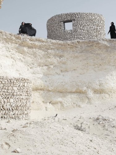 Dancers wearing a black attire in a desertic landscape 