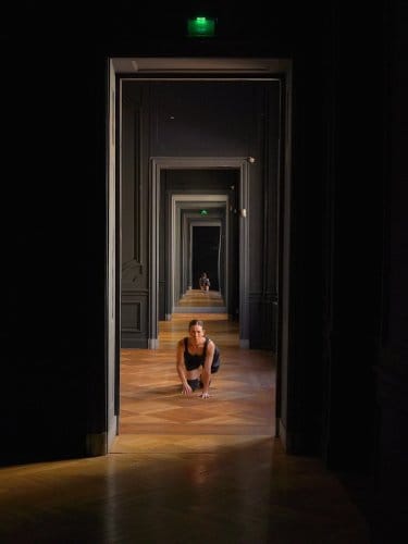 Dancer bending in a door frame along a corridor   