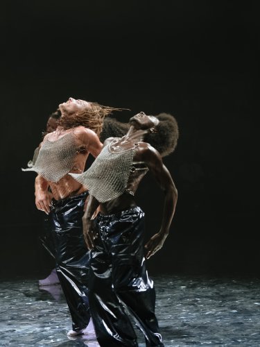 Two dancers with their heads thrown back, wearing chainmail t-shirts.