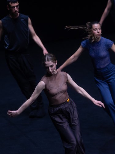 dancers aligned in a dark stage