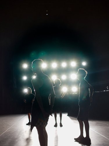 Danseurs dans l'obscurité d'un plateau avec des projecteurs en fond