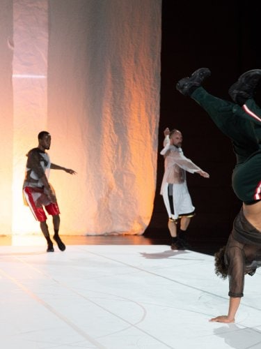 3 dancers aligned in the background and a breakdancer in the front scene