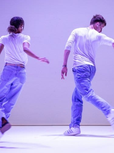 Danseurs en mouvement de dos, avec un fond mauve. 