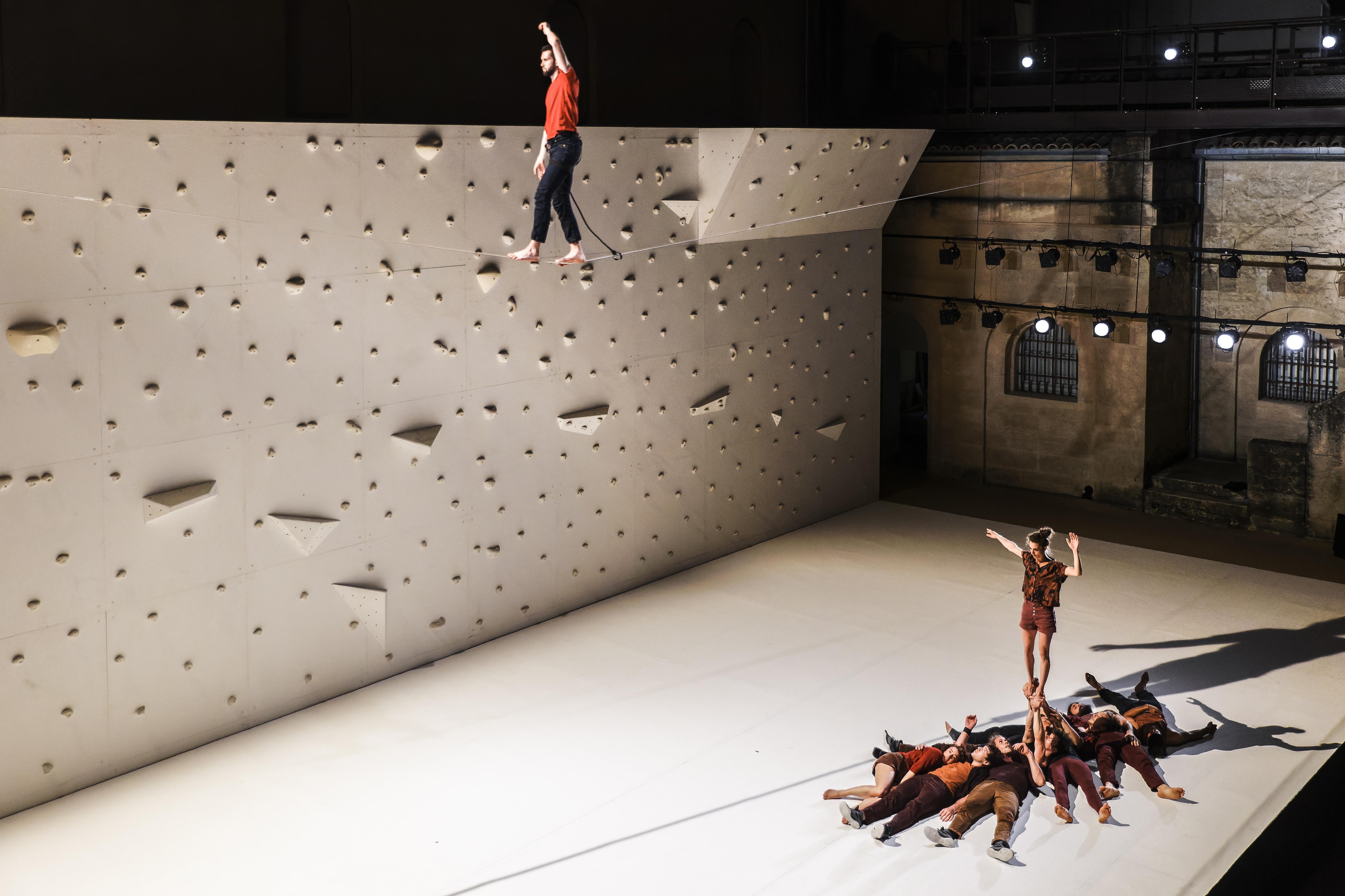 A dancer balancing on a rope above other dancers on stage 