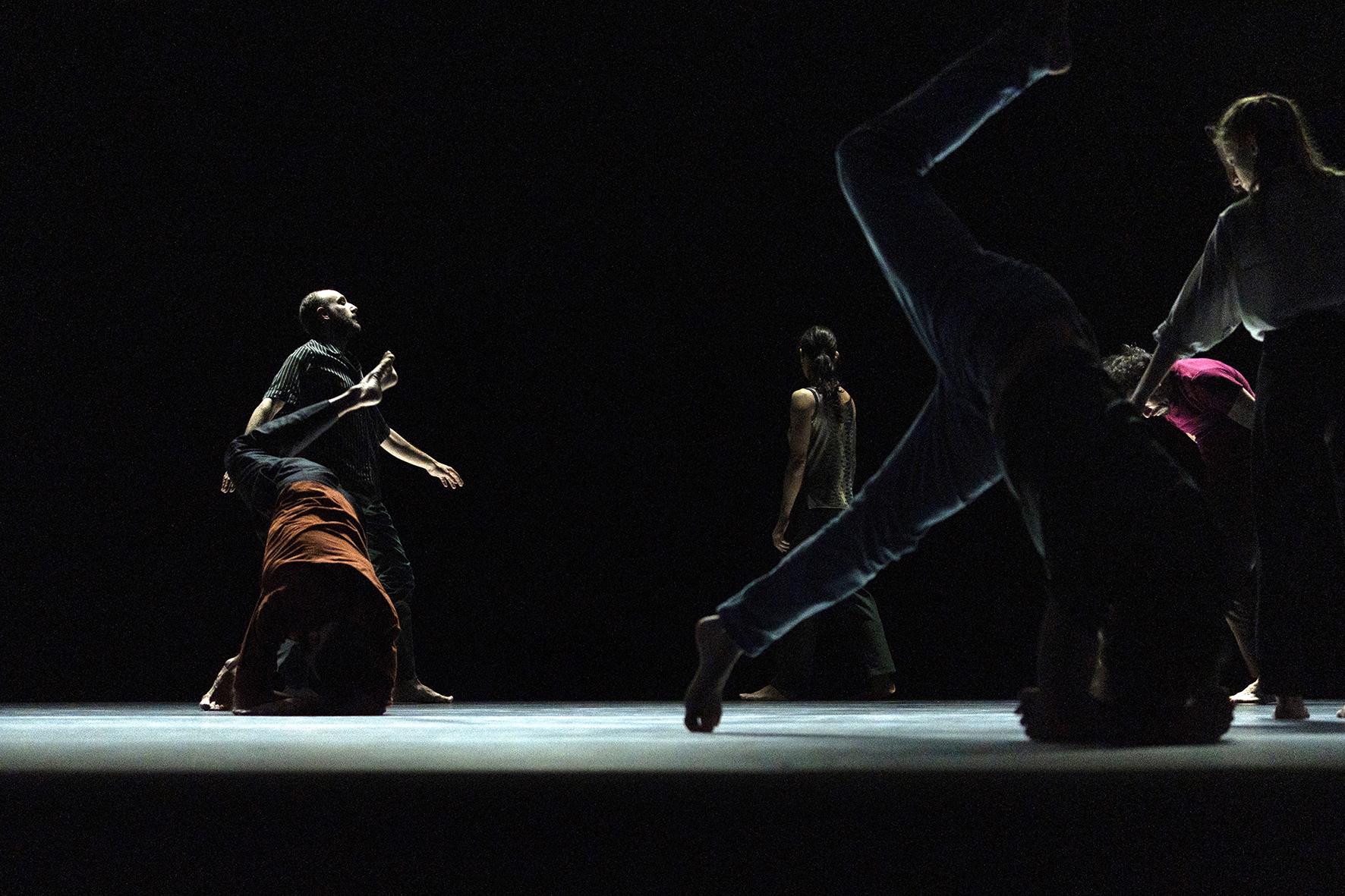 Danseurs se déplaçant sur un scène sombre 