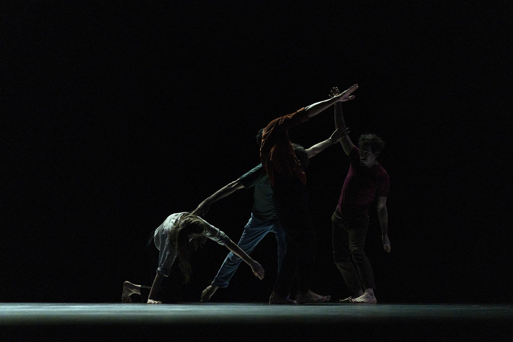 Danseurs créant une forme sur un scène sombre