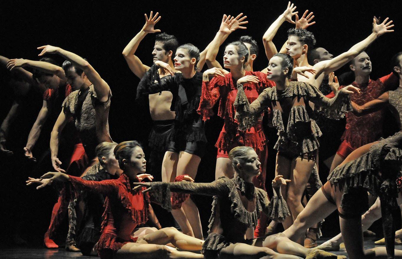 Groupe de danseurs debout et assis tendant les bras dans des directions différentes