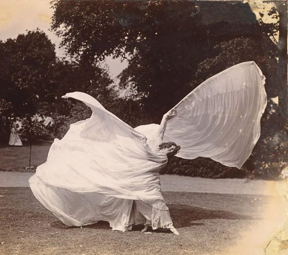 Dancer performing the Serpentine Dance with flowing white veils