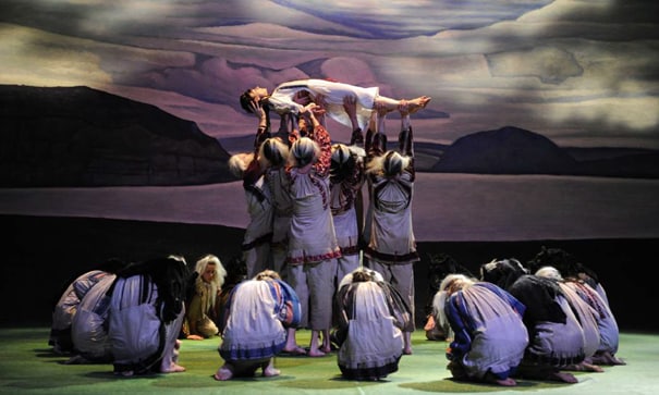 danseurs en cercle soulevant une danseuse allongée