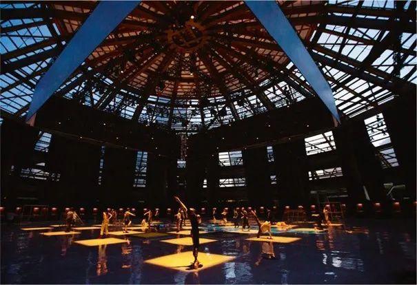 Dark auditorium with dancers dancing in square patches of light