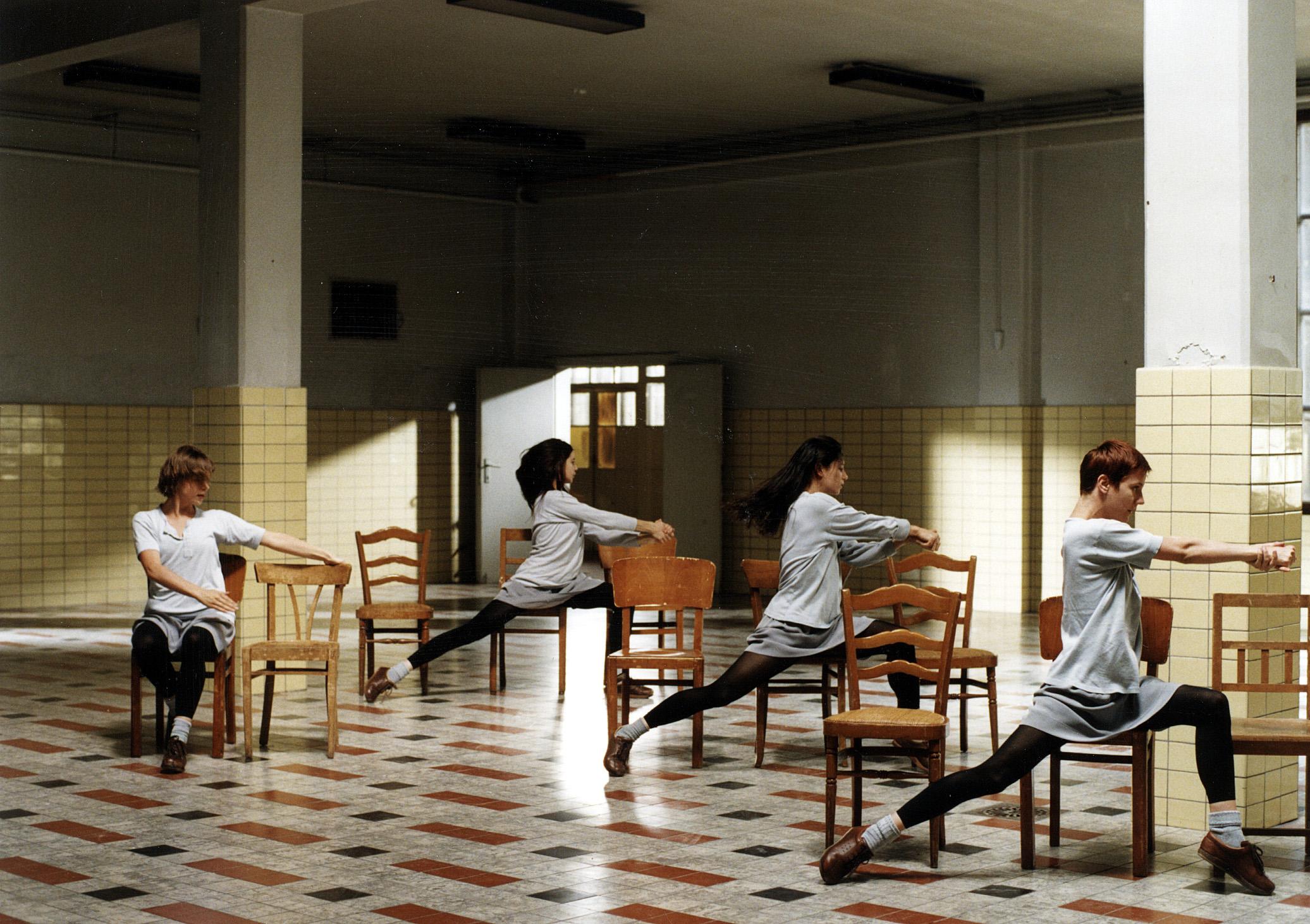 three women seated on chairs with their right arm raised