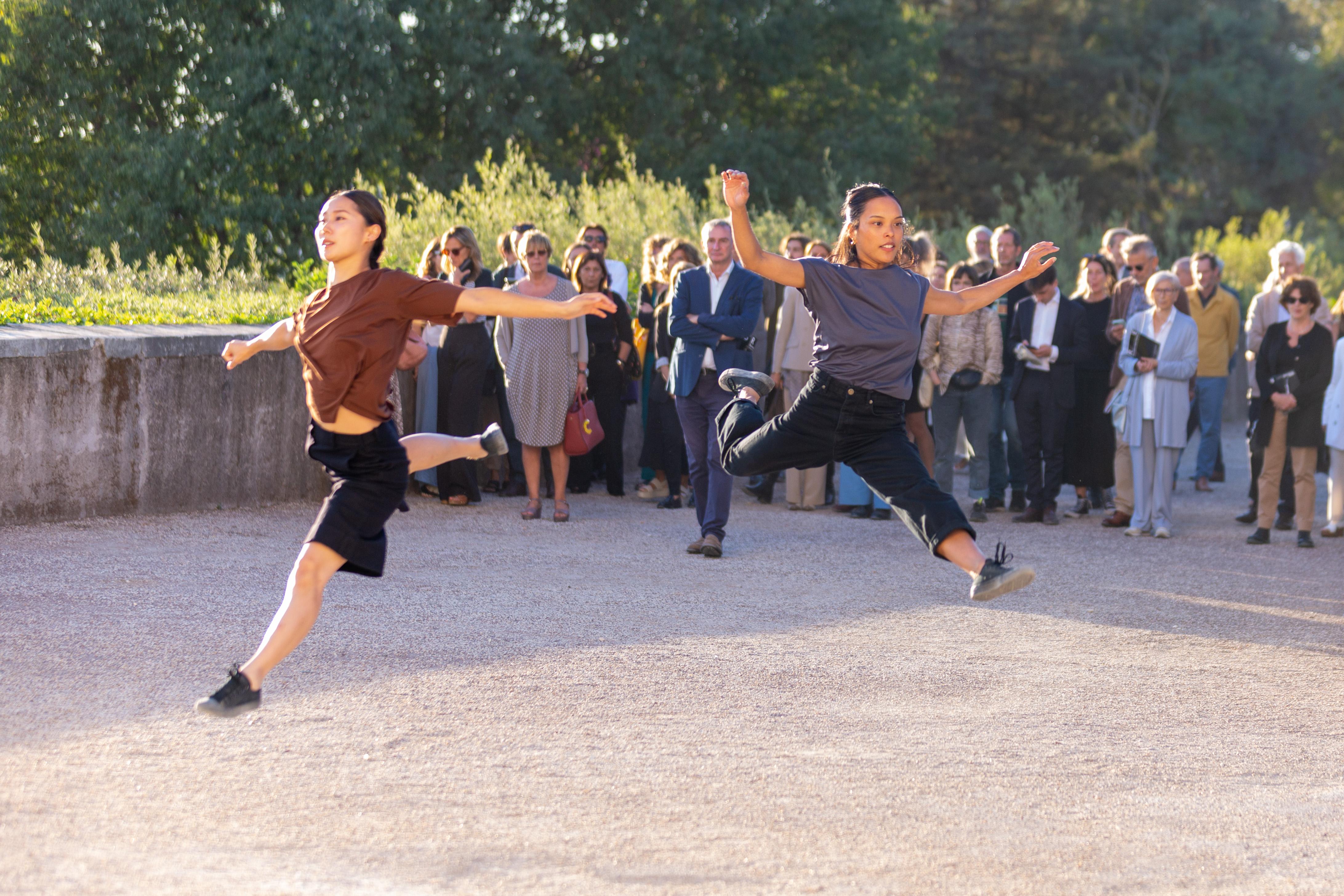 Two dancers jumping with the audience in the background