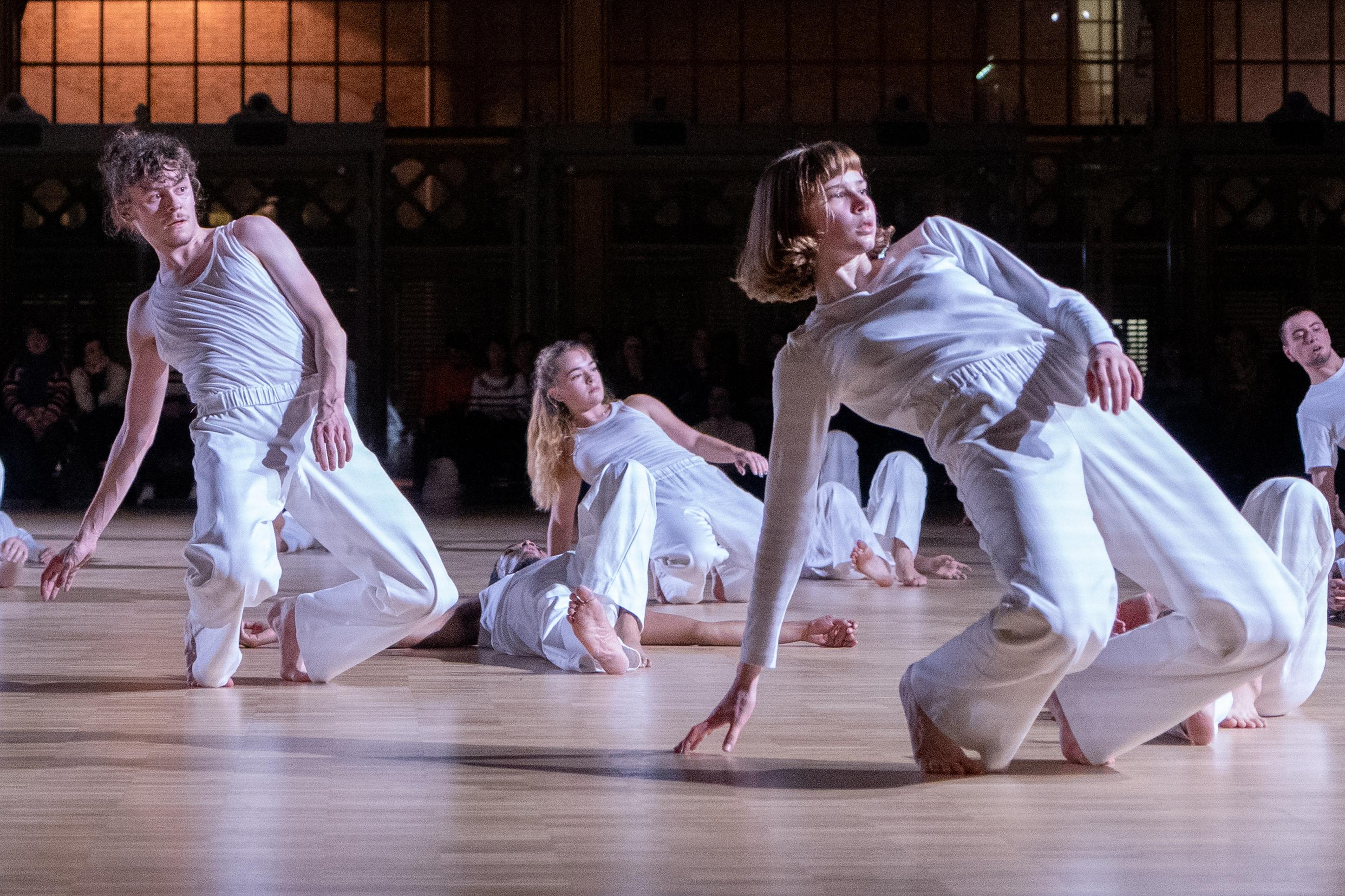 Dancers bent forward, one arm touching the ground