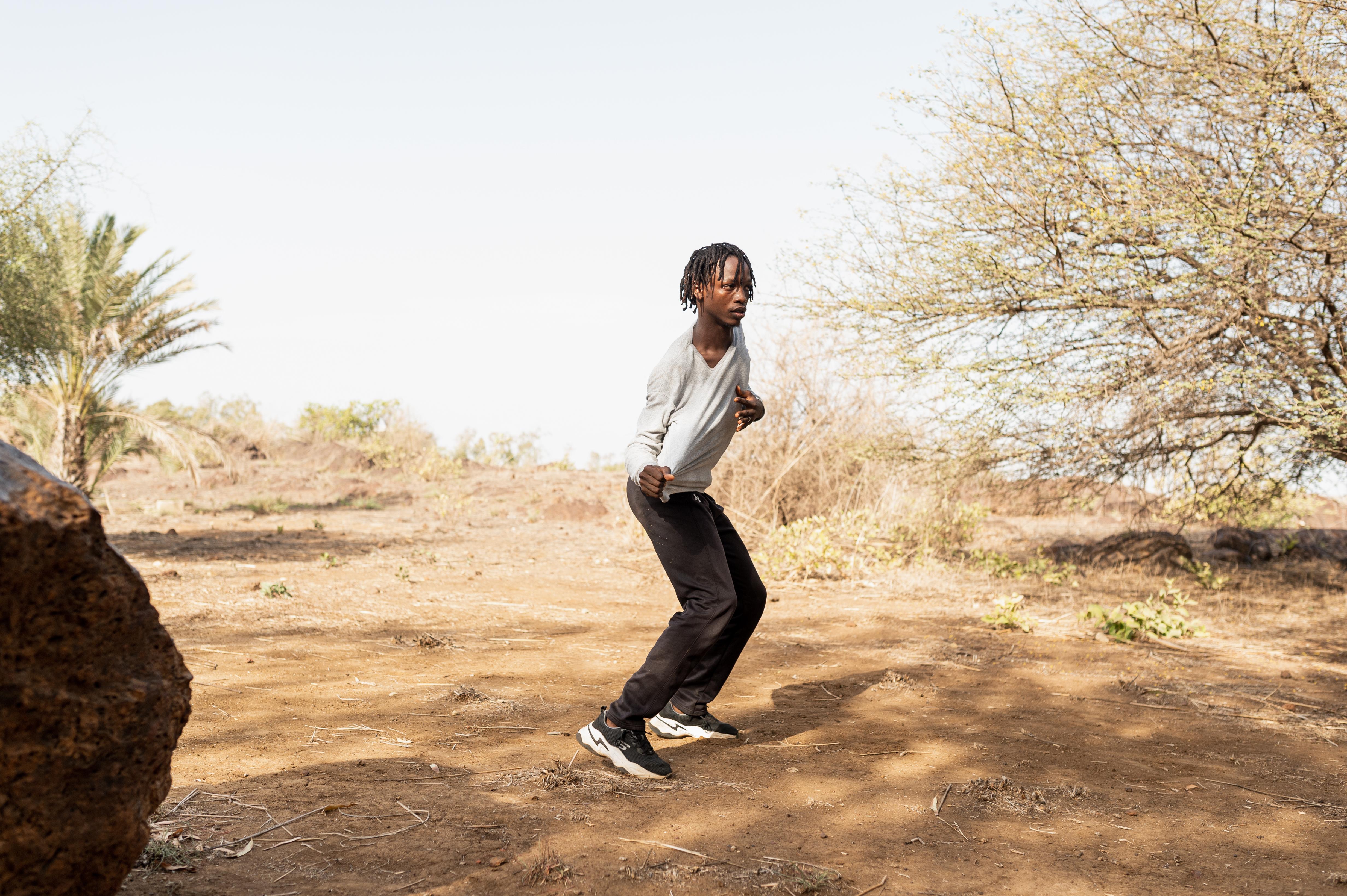 Dancer puling his grey t-shirt to the right