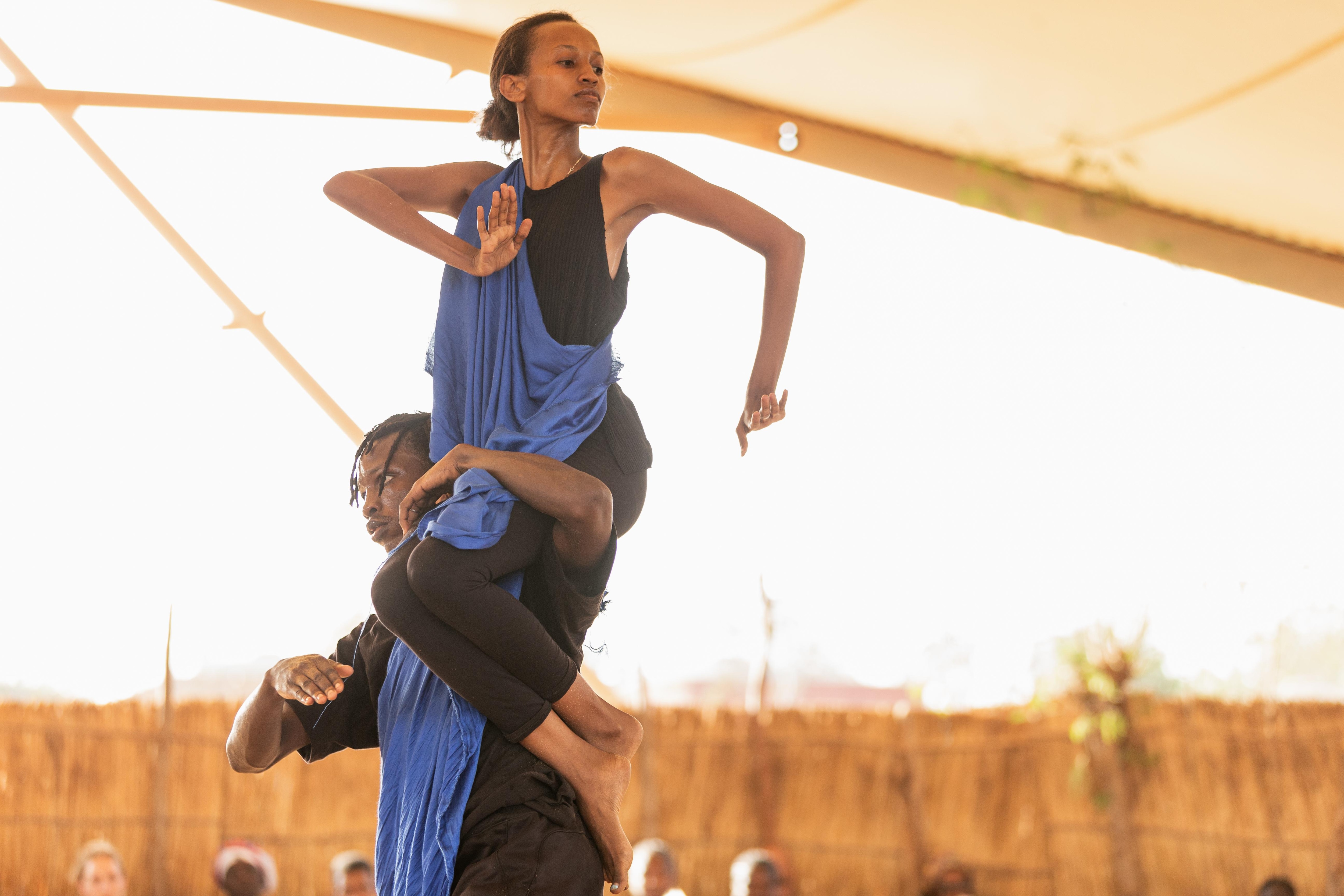 Un danseur tient une femme assise sur une de ses épaules