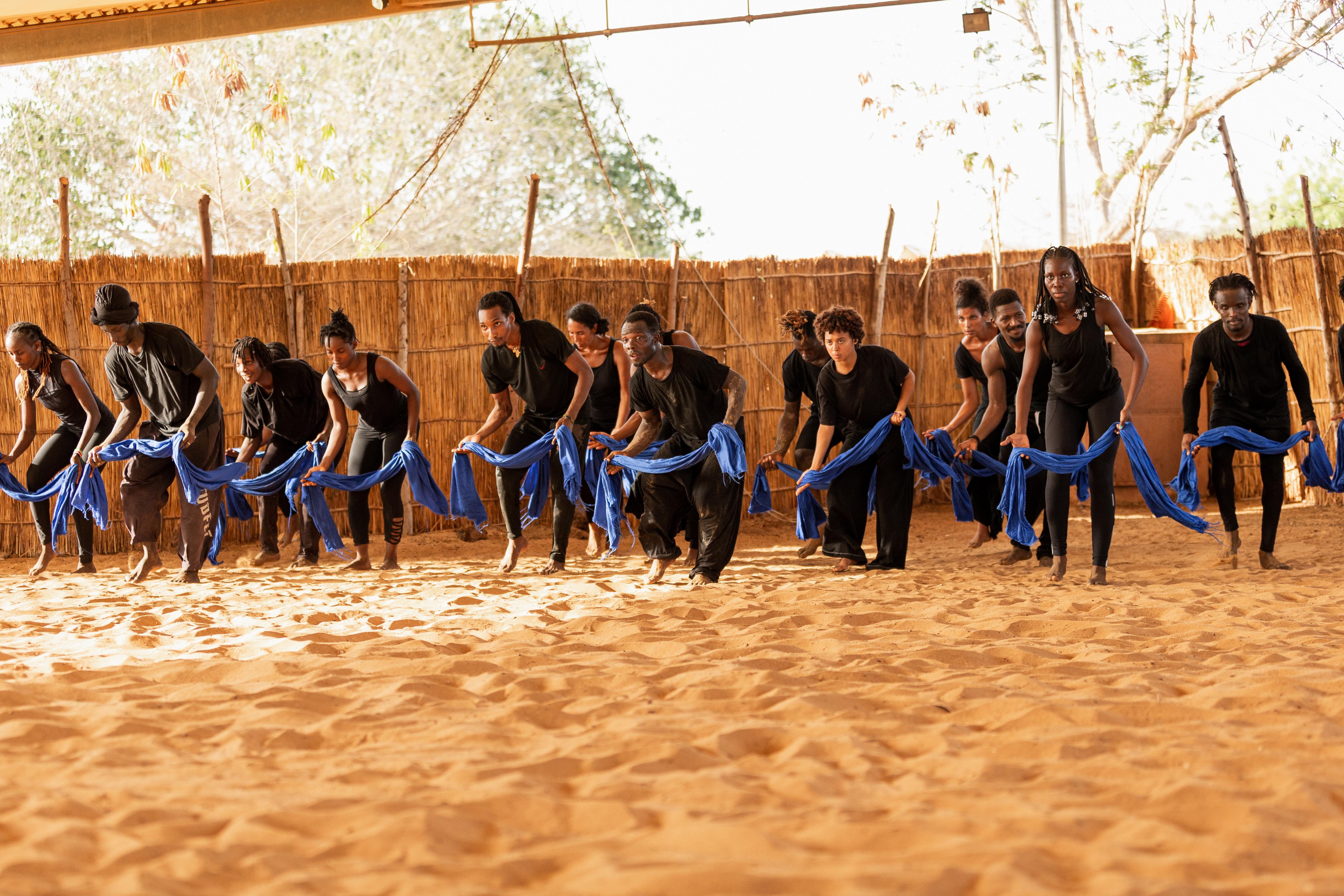 Dancers in lines, each holding a blue scarf