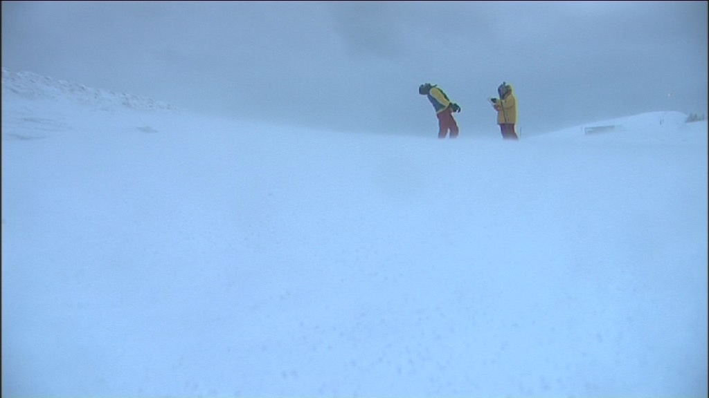 two men in the background, on a snowy ground and in the fog