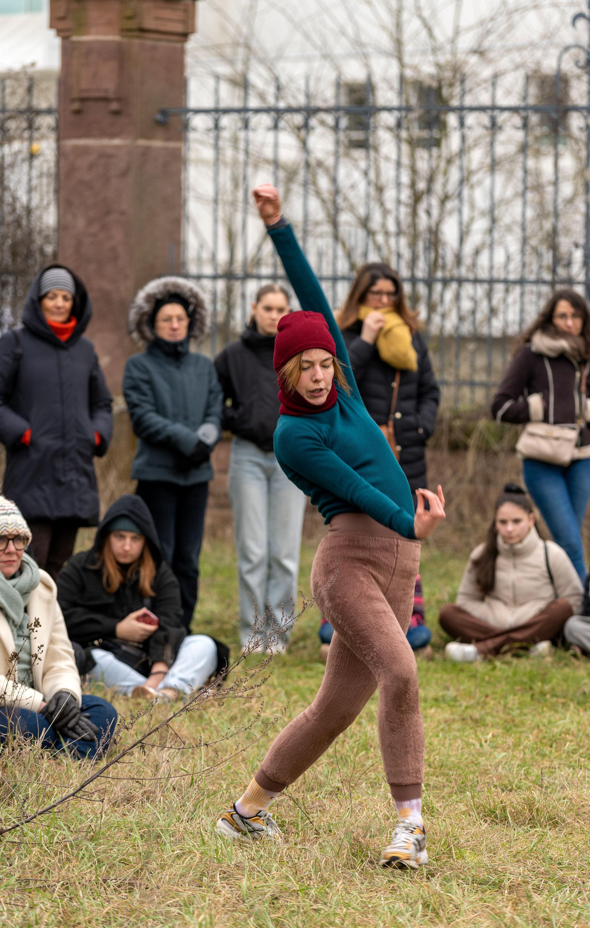 Danseuse en extérieur avec un pull bleu et un legging marron 