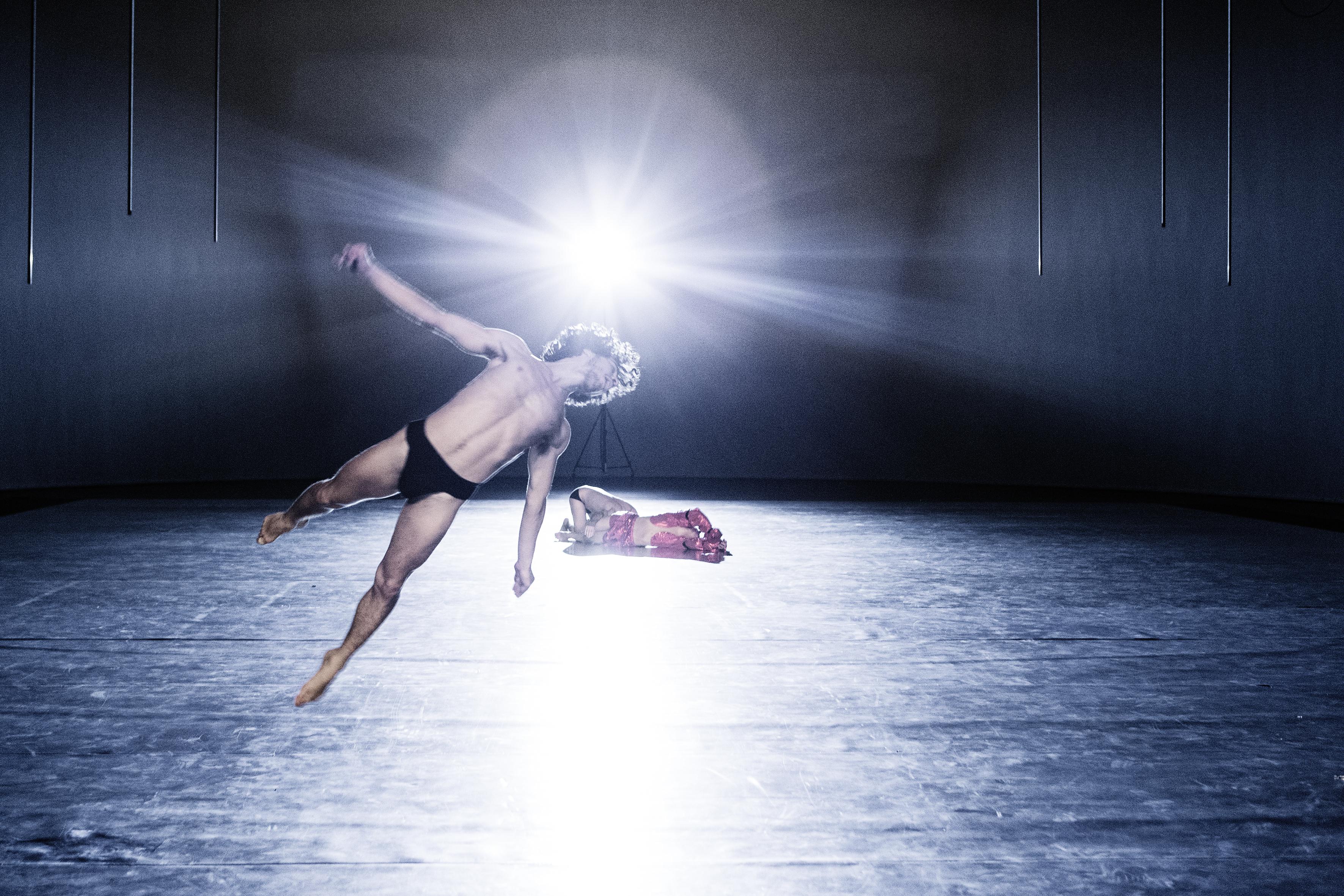 Danseur de 10000 gestes de Boris Charmatz sur scène, une lumière puissante en fond