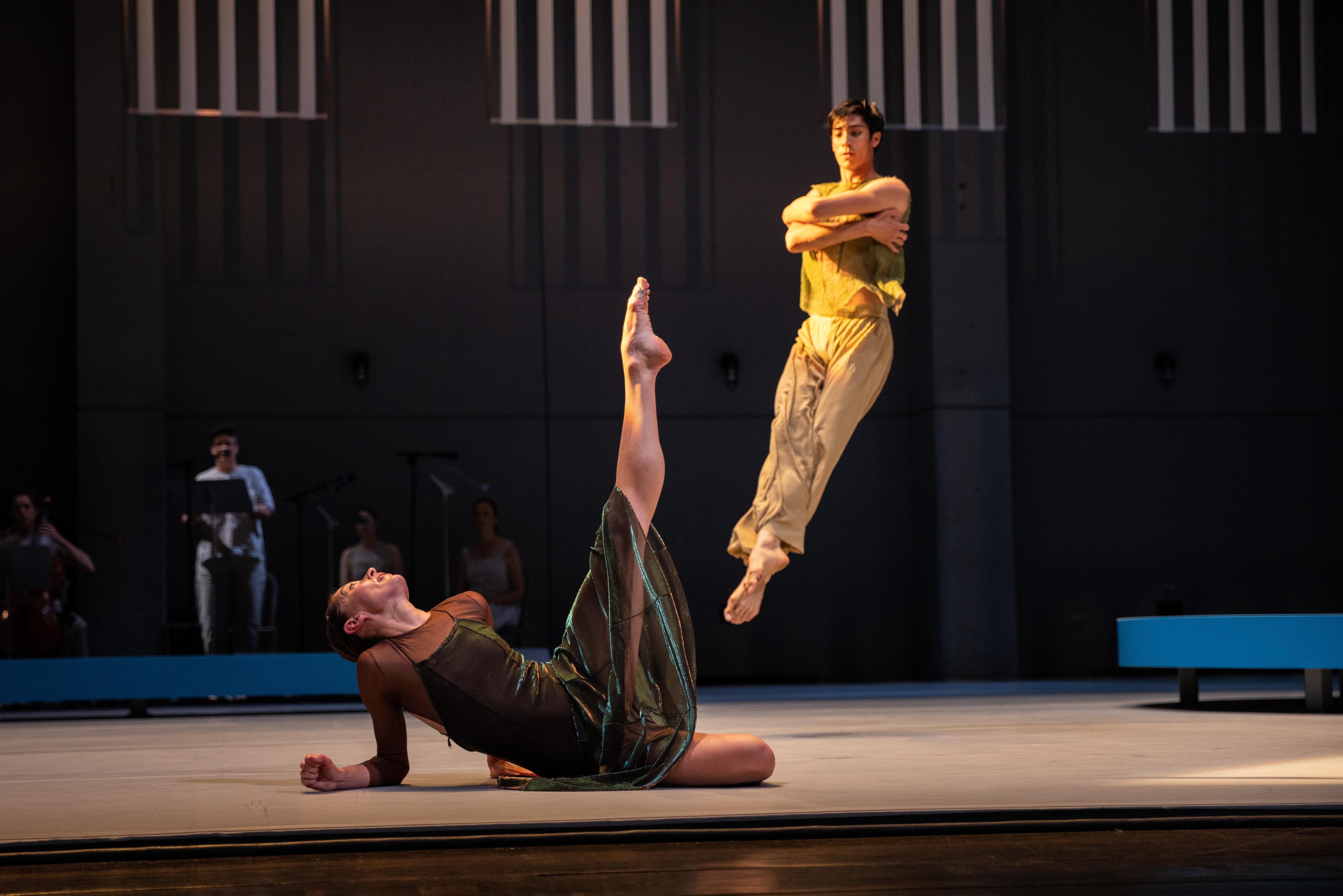 Melissa Toogood on the ground with one leg extended to the sky, Zachary Gonder jumping in the background